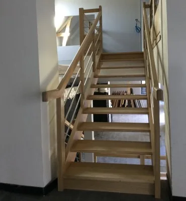 Escalier droit à crémaillère en bois massif avec garde-corps en inox, design moderne et épuré, idéal pour un intérieur contemporain.