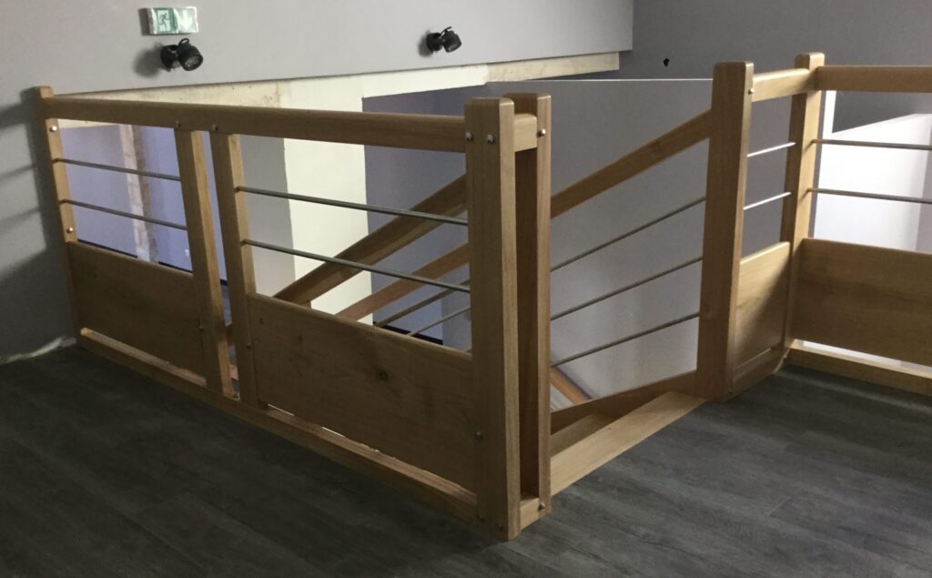 Garde-corps sur mesure en bois et inox à Autheuil-Anthouillet, installé sur une mezzanine moderne, sécurisant l’accès à l’escalier.