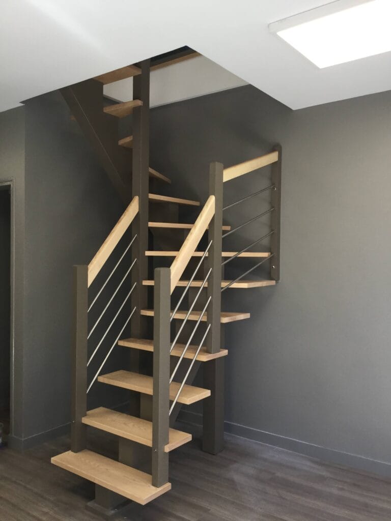 Escalier sur mesure droit limon central bois sur mesure dans l'Eure (27) – Escalier Eure garde corps- On peut imaginer une famille propriétaire d’un pavillon à Vernon, qui souhaite ouvrir la cuisine sur le séjour et en profiter pour changer un escalier en bois sombre et fermé. L’escalier existant, très massif, gêne la circulation et coupe la lumière venant de la baie vitrée donnant sur le jardin.​ L’artisan escalier propose un escalier sur mesure en frêne, avec structure en bois et garde-corps bois équipé de barres acier noir sur la montée et le palier. Les mêmes personnes viennent prendre les mesures sur place, fabriquent l’escalier à l’atelier puis assurent la pose, ce qui garantit un ajustement précis malgré les irrégularités d’une maison déjà ancienne.​Vernon, escalier sur mesure, escalier en frêne