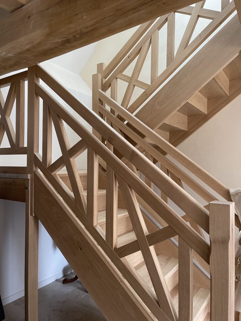 Escalier sur mesure en bois massif avec palier, limon entaillé et garde-corps motifs croix de Saint-André.